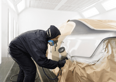 Service worker painting car in auto service